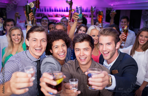 Portrait of enthusiastic crowd drinking cocktails in nightclub