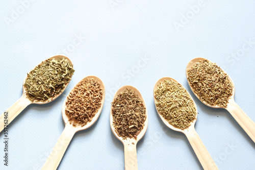 Wooden spoons with spices. Collection spices on the blue background.