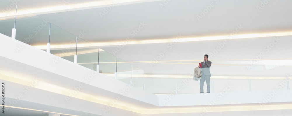 Businessman at glass balcony railing in modern office