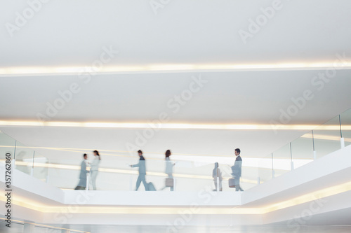 Business people walking along elevated walkway in airport