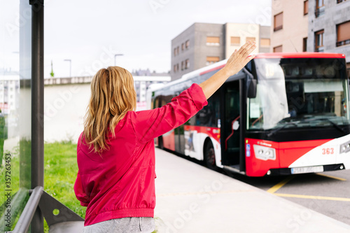 Woman stopping bus at bus stop