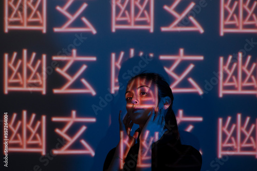 Young woman hidden by light patterns on a wall photo