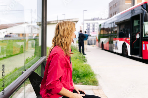 Woman with surgical mask at bus stop