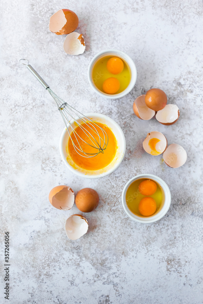 Wire whisk, eggshells and bowls with egg yolks Wire whisk, eggshells and bowls with egg yolks