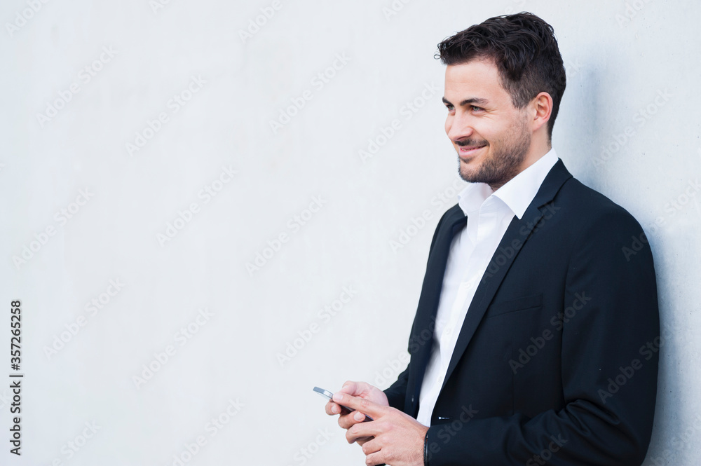 Smiling businessman wearing suit holding smartphone Smiling businessman wearing suit holding smartphone