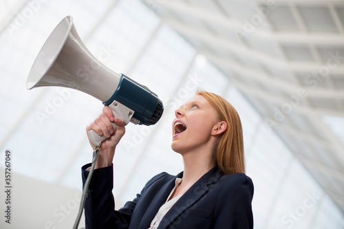 Businesswoman shouting into bullhorn photo