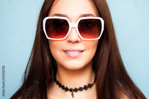 Closeup woman portrait in sunglasses on a blue background. Brunette wearing sunglasses.