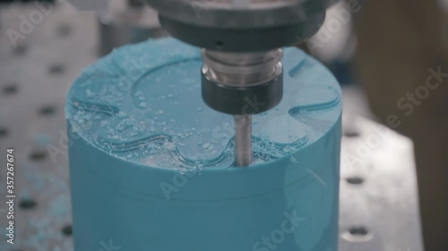Industrial milling machine at work with blue wax candle blank. Scene. Close up of milling machine making beautiful ornament on wax figure or candle. photo