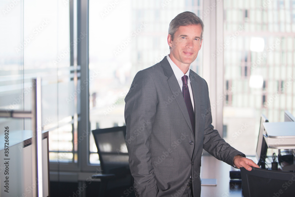 Businessman standing at desk in office Businessman standing at desk in office
