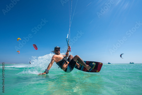 kiter does a difficult trick on a background of transparent water and blue sky © ohrim