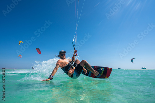 kiter does a difficult trick on a background of transparent water and blue sky