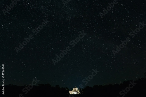 White palace among the trees on the background of the starry night. Starry night