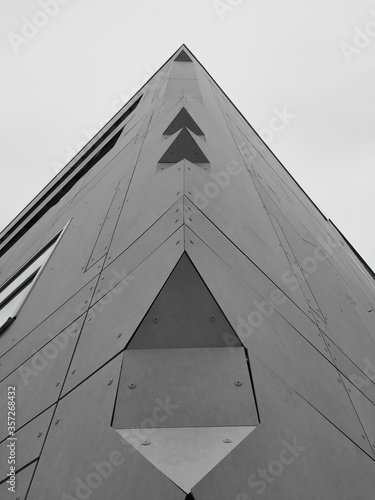 The corner of a concrete panel clad building with chamers and edges creating perspective lines on a monochrome background photo