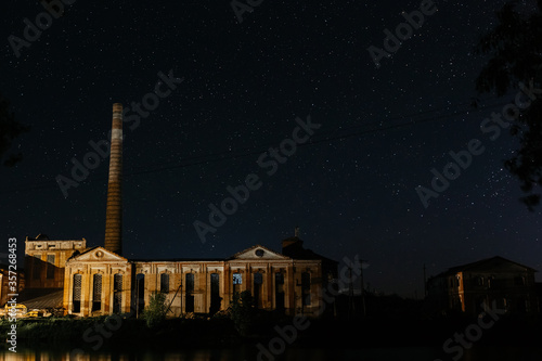 Old factory with high high pipe on the background of the starry night. Starry night