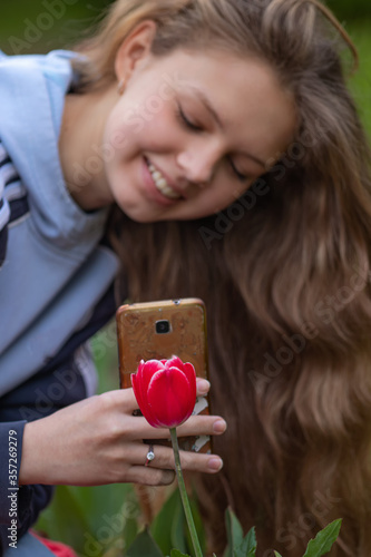 A teenage girl photographs flowers on her mobile phone. Mobilography. photo