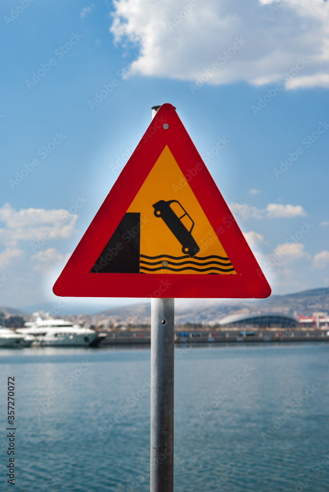 Road traffic sign of car falling into the water from a pier