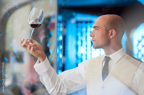 Waiter examining glass of wine in restaurant