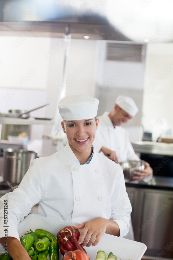 Chef carrying tub of vegetables in restaurant kitchen Chef carrying tub of vegetables in restaurant kitchen
