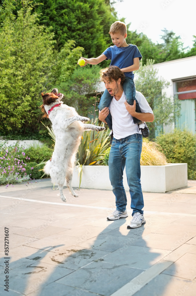 Obraz premium Father and son playing with dog outdoors