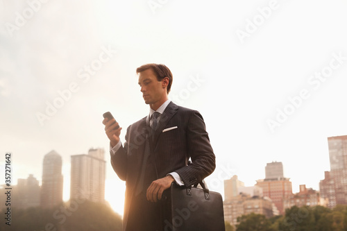 Businessman using cell phone in urban park