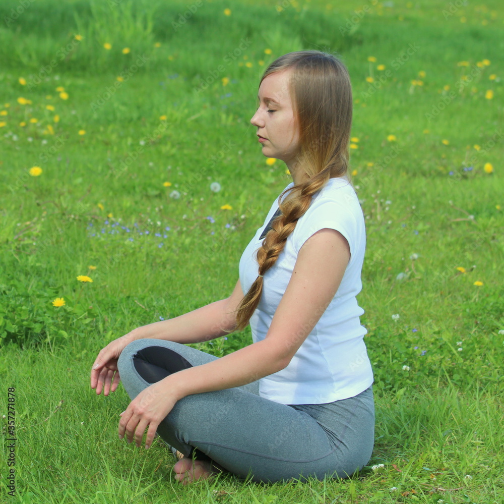 Fototapeta premium Young woman of European appearance does yoga in summer nature