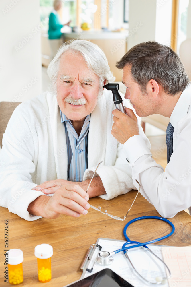 Obraz premium Doctor examining older man's ear at house call