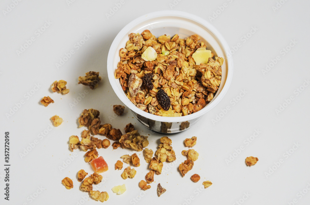 Muesli in a round jar on a white background with sprinkled crumbs. Diet breakfast with milk or yogurt. Selective focus. Muesli in a round jar on a white background with sprinkled crumbs. Diet breakfast with milk or yogurt. Selective focus.