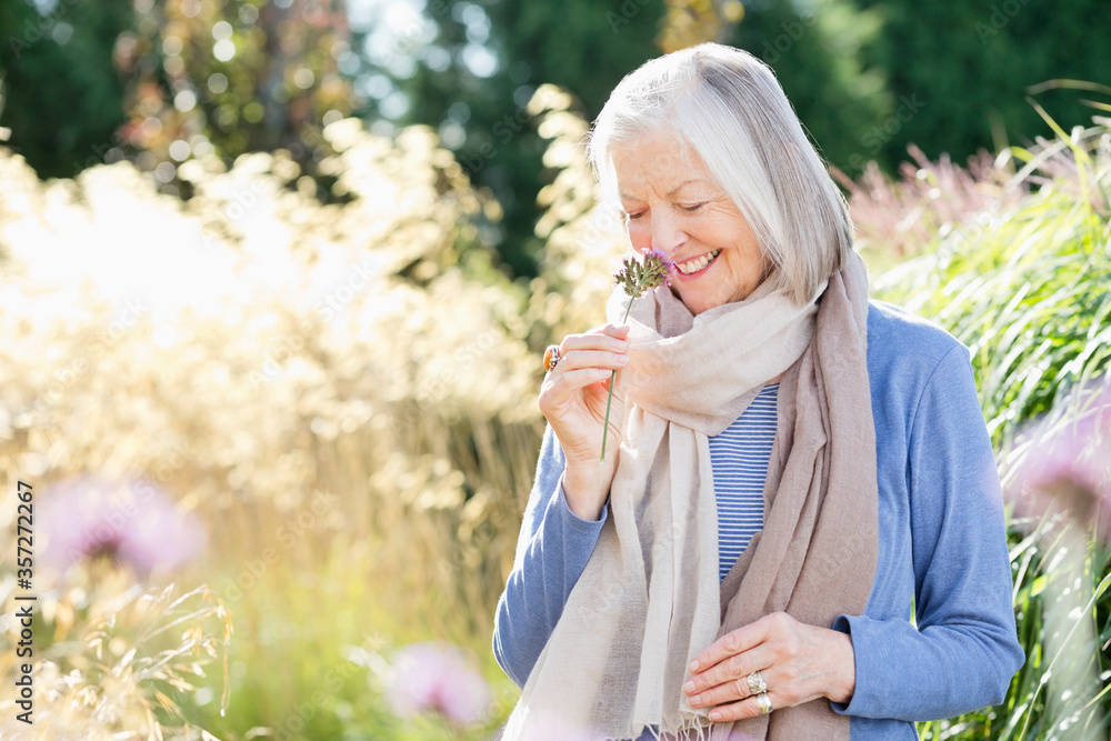 Older woman smelling flowers outdoors Older woman smelling flowers outdoors