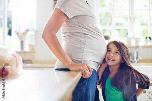 Girl listening to pregnant mothers belly
