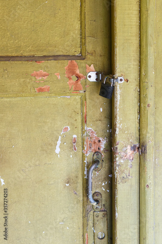 An abandoned house with an old and ruined door on a padlock