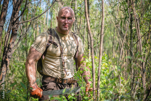 Fotografi Adventurer man with a machete in the green forest concept.