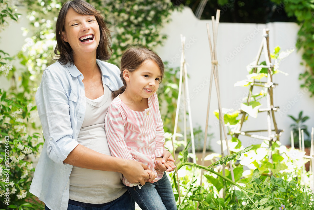 Pregnant mother and daughter gardening together