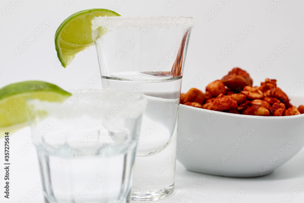 Caballito shot de tequila con cacahuates enchilados fondo blanco