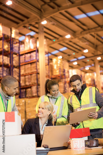 Businesswoman and workers talking in warehouse