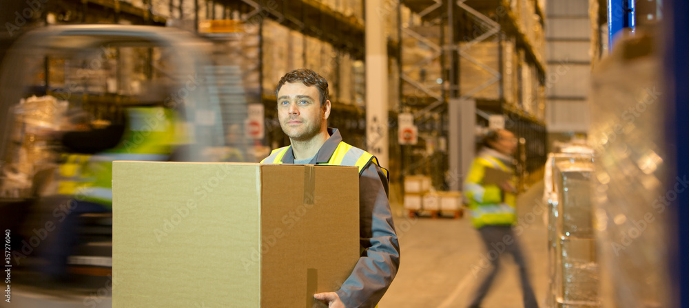Worker carrying box in warehouse - obrazy, fototapety, plakaty 