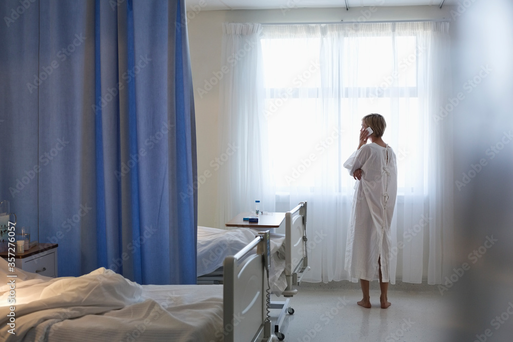 Patient in gown talking on cell phone in hospital room Patient in gown talking on cell phone in hospital room
