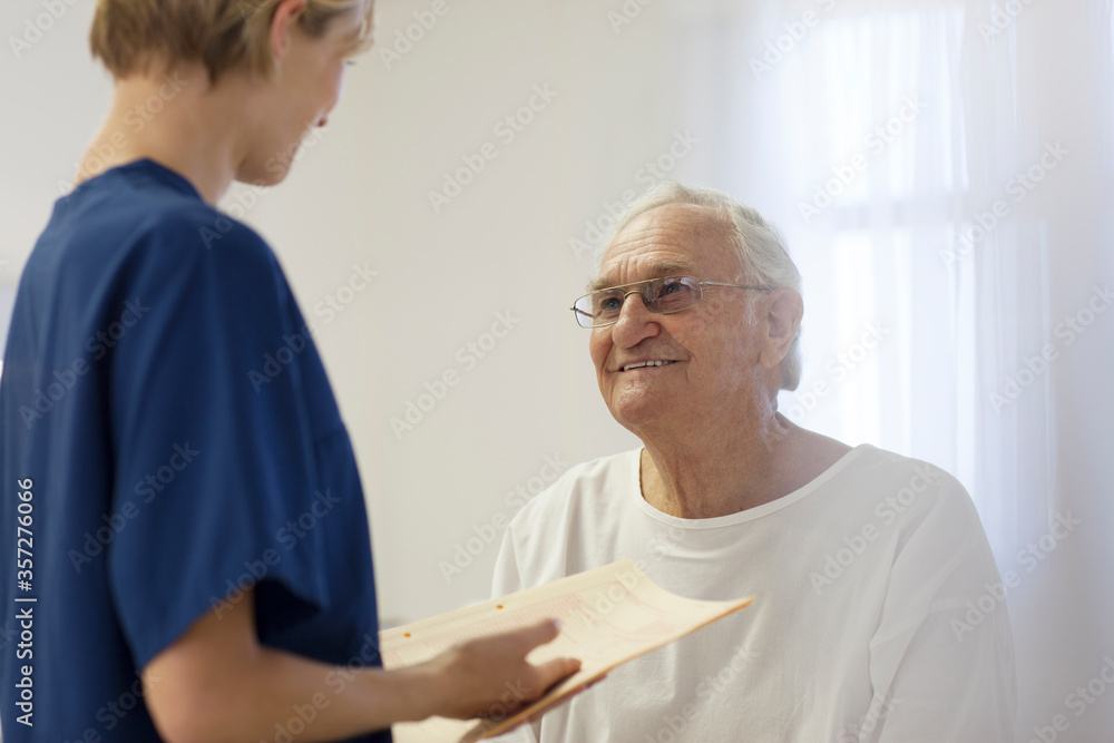 Fototapeta premium Nurse talking to older patient in hospital room