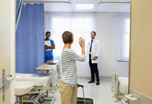 Patient waving to doctor in hospital room