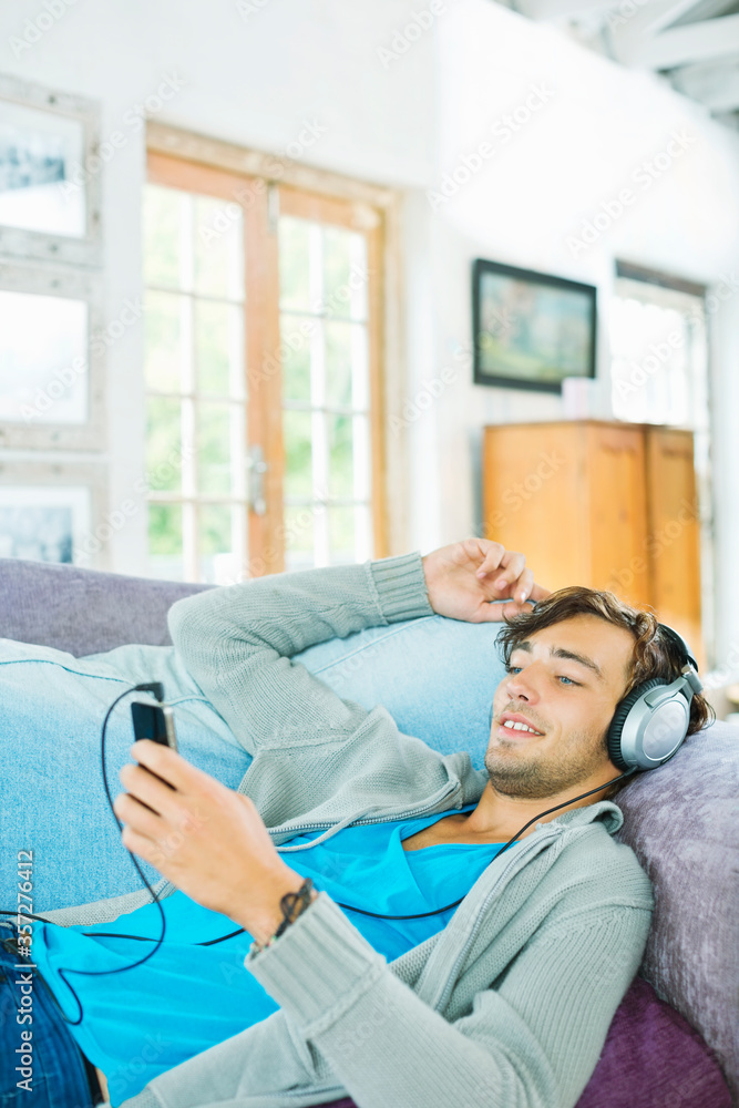 Obraz premium Man listening to headphones on sofa