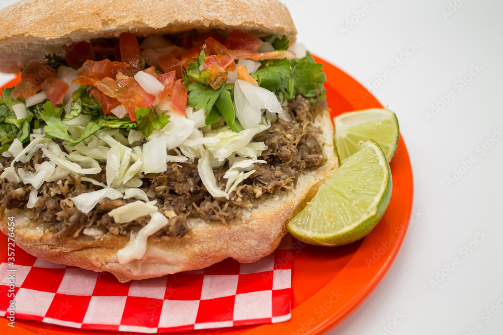 Tacos y tortas de barbacoa sobre mantel de cuadros rojos y fondo blanco