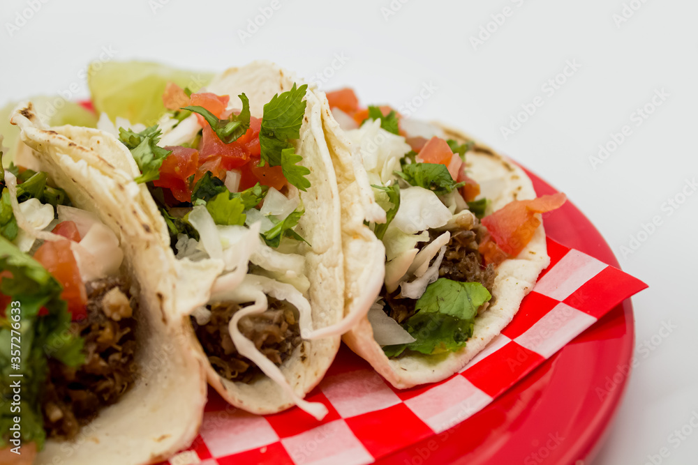 Tacos y tortas de barbacoa sobre mantel de cuadros rojos y fondo blanco Tacos y tortas de barbacoa sobre mantel de cuadros rojos y fondo blanco