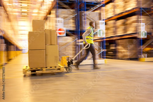 Blurred view of worker carting boxes in warehouse photo
