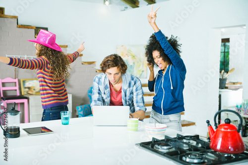 Tablou pe pânză Women dancing around man in kitchen