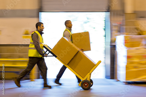 Workers carting boxes in warehouse