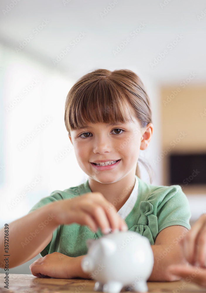 Girl filling piggy bank on counter