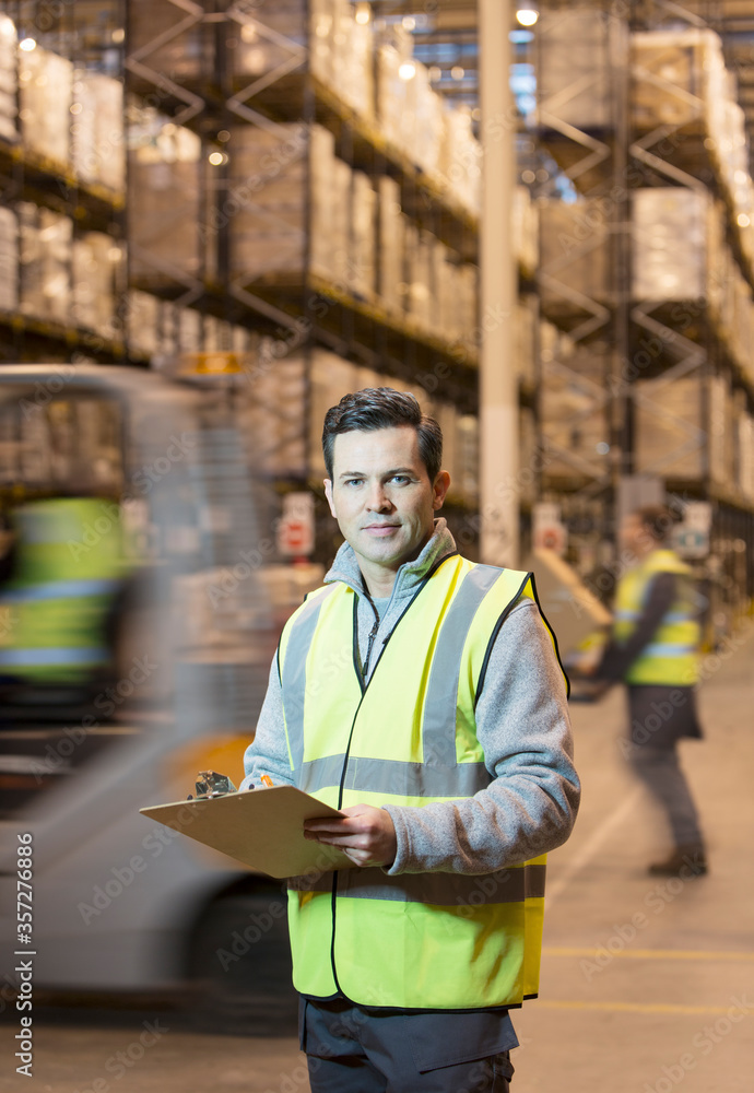 Worker writing on clipboard in warehouse Worker writing on clipboard in warehouse