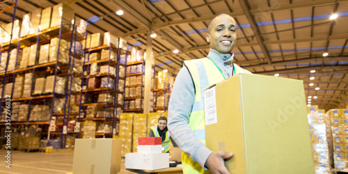 Worker carrying box in warehouse