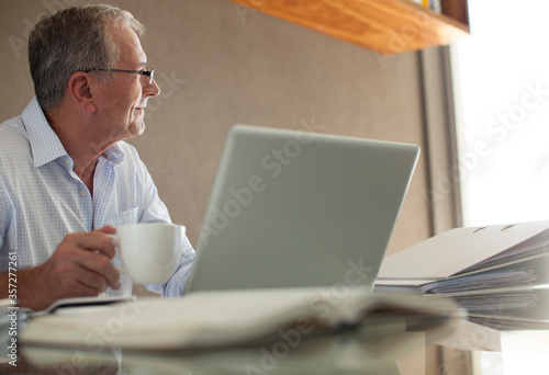 Businessman having cup of coffee at laptop