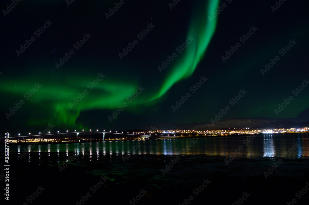 majestic aurora borealis over fjord, mountain and bridge in the arctic circle