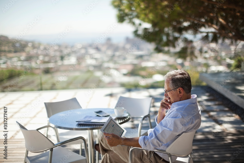 Older man using tablet computer outdoors